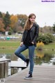 A woman in a black jacket and jeans standing on a dock.