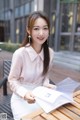 A woman sitting at a table holding a book.