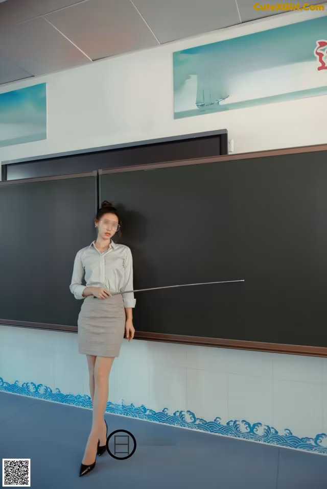 A woman standing in front of a blackboard in a classroom.