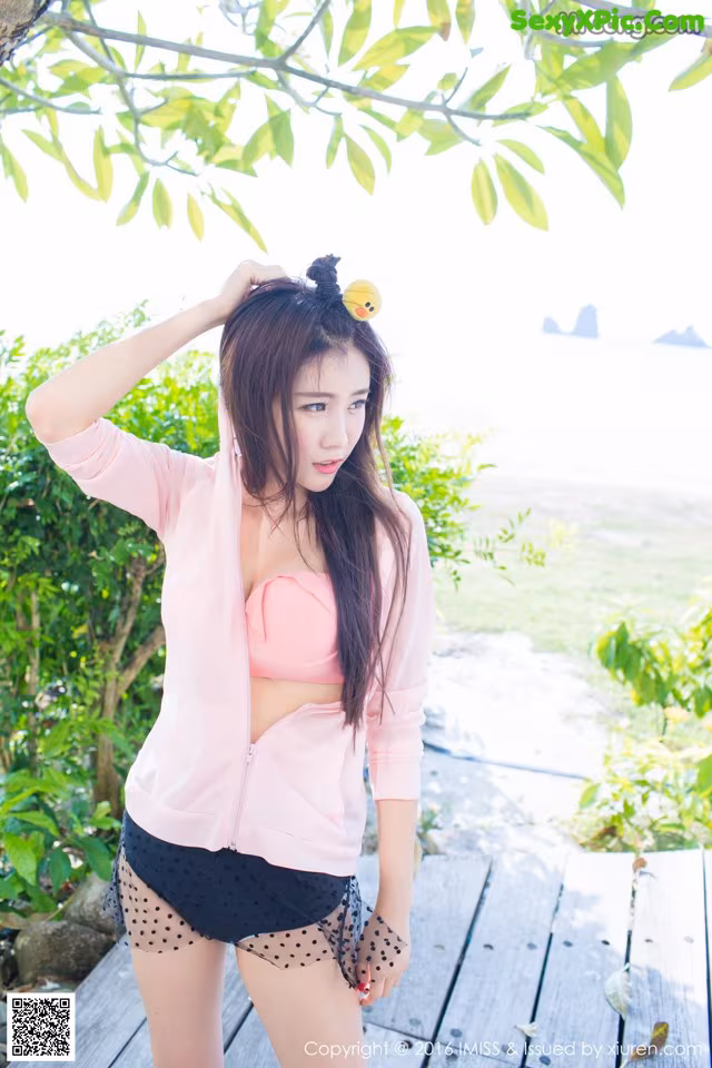 A woman in a pink top and black shorts posing for a picture.