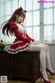 A woman in a red and white dress sitting on a dresser.