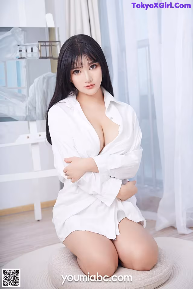 A woman in a white shirt sitting on a round rug.
