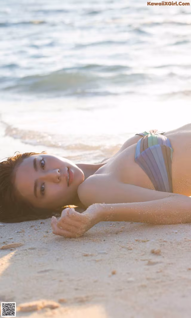 A woman laying on the beach in a bikini.