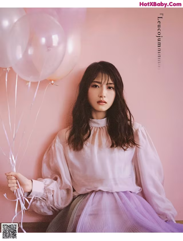 A woman sitting on a bench holding a bunch of balloons.