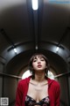 A woman in a red jacket is standing in a tunnel.