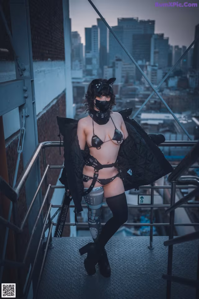 A woman in lingerie and a mask standing on a balcony.
