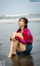 A woman sitting on the beach with her legs crossed.