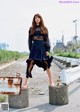 A woman in a black dress standing on a concrete block.