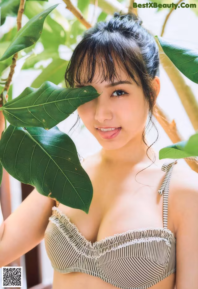 A woman in a bikini posing in front of a tree.