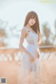 A woman in a white dress standing in a field.