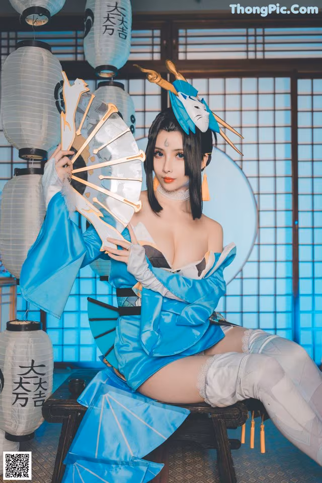 A woman in a blue and white outfit holding a fan.