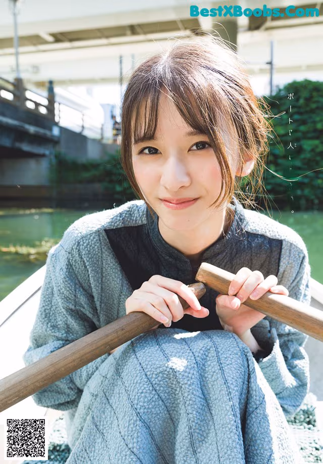 A young woman sitting on a boat holding a wooden stick.