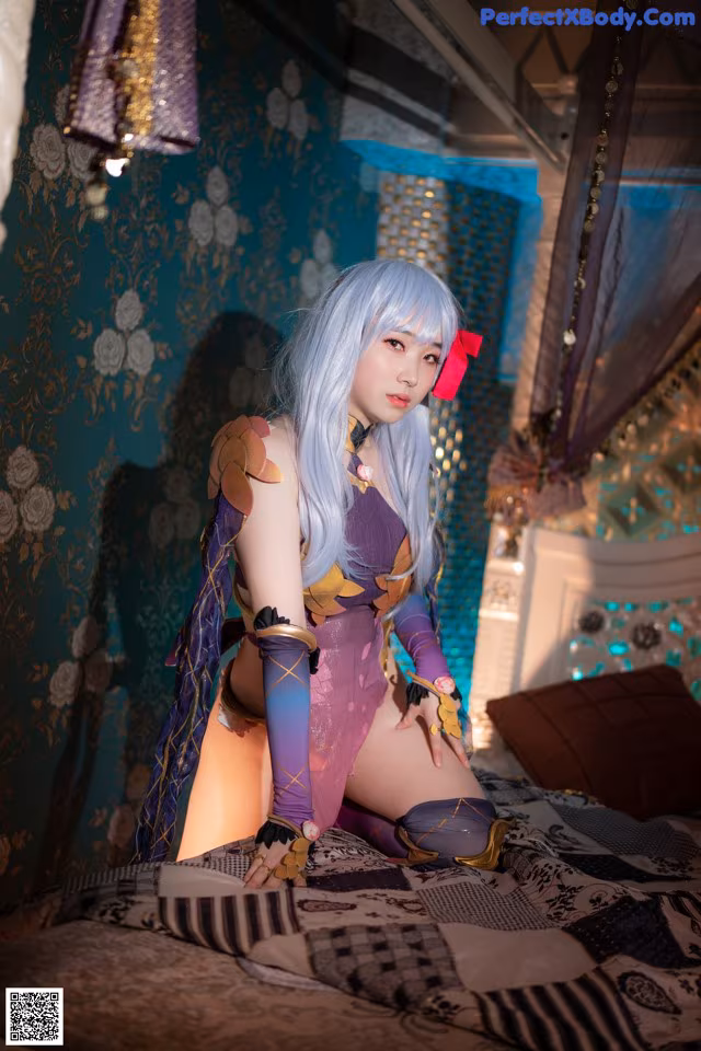 A woman in a purple outfit sitting on a bed.