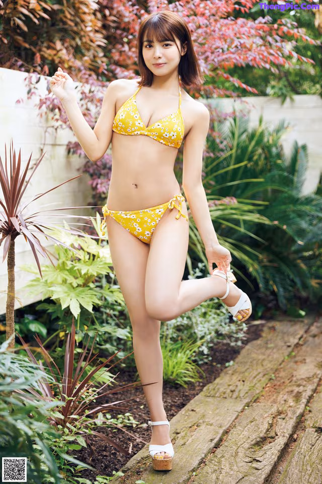 A woman in a yellow bikini posing for a picture.