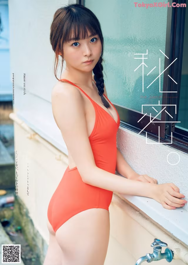 A woman in a red bathing suit leaning against a window.
