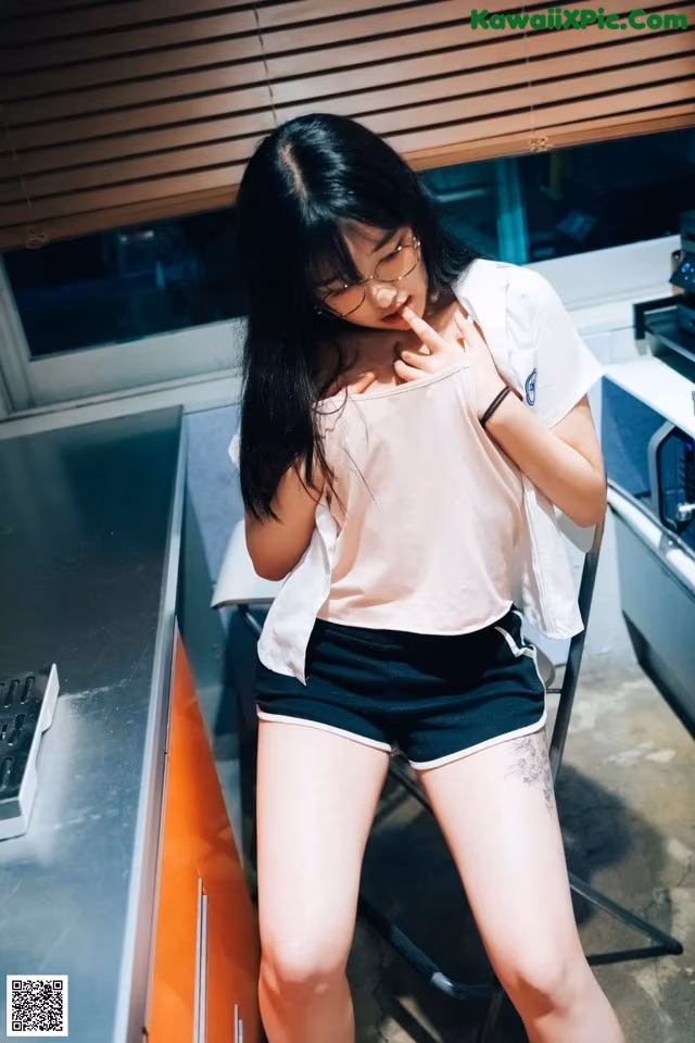 A woman in a white shirt and black shorts posing for a picture.